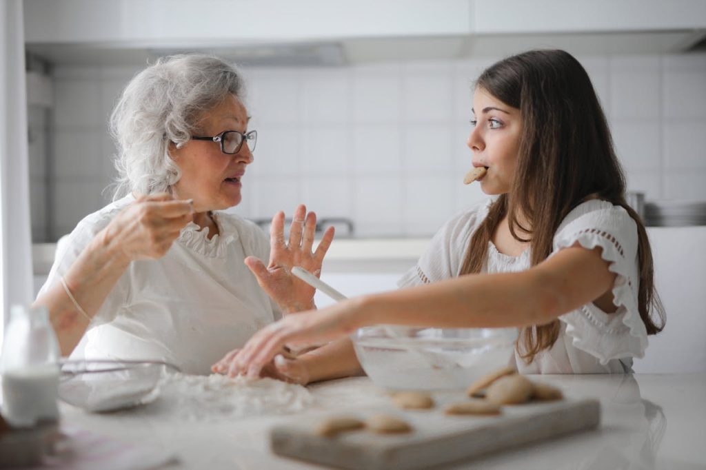 pexels-photo-3768146 Calm senior woman and teenage girl in casual clothes looking at each other and talking while eating cookies and cooking pastry in contemporary kitchen at home